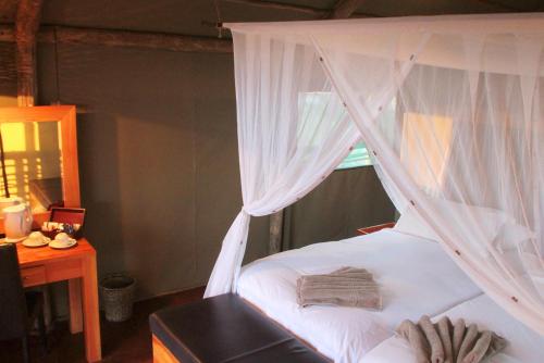 a bedroom with a white bed with a canopy at Suricate Tented Kalahari Lodge in Hoachanas