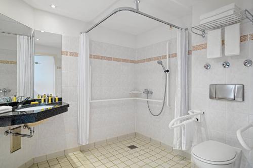 a bathroom with a shower and a toilet and a sink at Leipzig Marriott Hotel in Leipzig