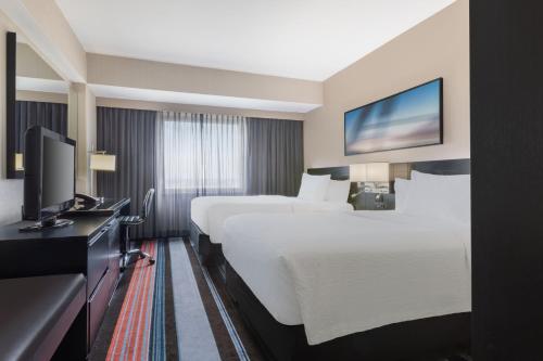 a hotel room with two beds and a flat screen tv at Courtyard by Marriott New York JFK Airport in Queens