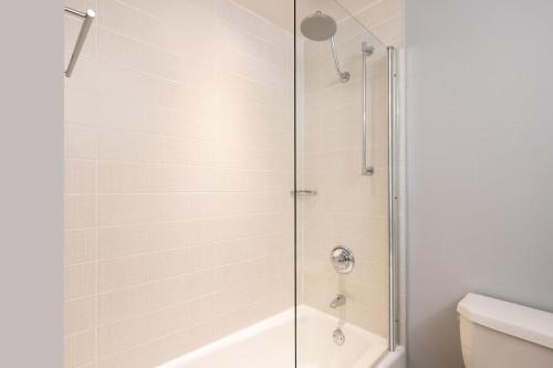 a shower with a glass door in a bathroom at Courtyard by Marriott New York JFK Airport in Queens
