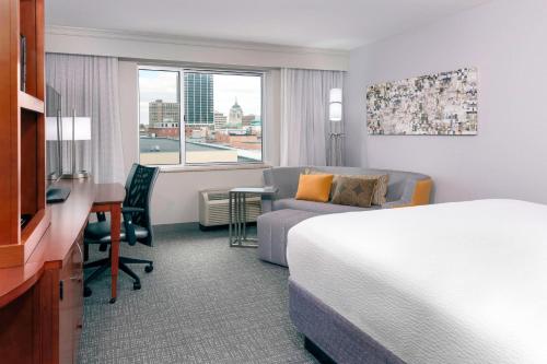 a hotel room with a bed and a desk and a couch at Courtyard Fort Wayne Downtown at Grand Wayne Convention Center in Fort Wayne