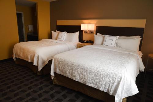 two beds in a hotel room with white sheets at TownePlace Suites by Marriott Lawrence Downtown in Lawrence