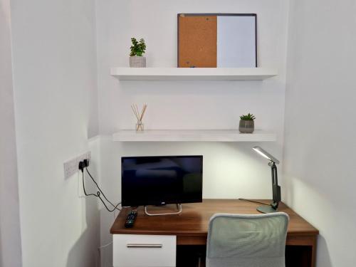 a computer desk with a monitor and a chair at Incredible Private Rooms All with Private Bathrooms in a Fully Serviced House next to City Centre with Free Parking in Coventry