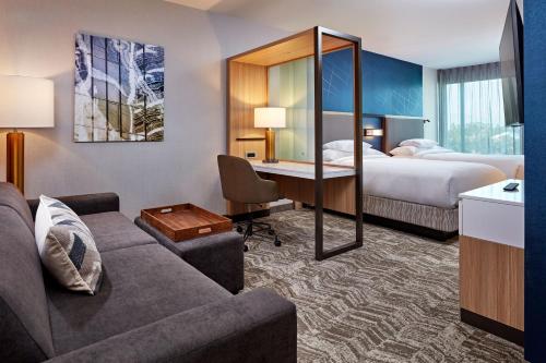 ダウニーにあるSpringHill Suites by Marriott Los Angeles Downeyのソファ、ベッド、デスクが備わるホテルルームです。