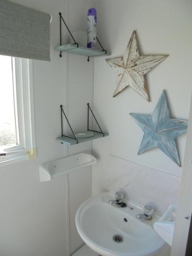 a bathroom with a sink and two stars on the wall at Highfields and Haven 8 Berth Tahiti in Lincolnshire