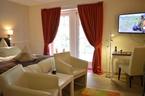 a bedroom with a bed and a tv and a window at Landhaus Zum Heidewanderer mit THERMEplus in Bad Bevensen