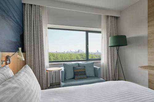a bedroom with a bed and a chair and a window at Marriott Hotel The Hague in The Hague