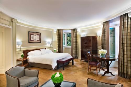 ローマにあるマリオット グランド ホテル フローラのベッドとデスクが備わるホテルルームです。