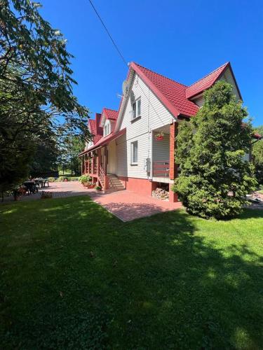 a large white house with a red roof and a yard at Dom gościnny Krasne in Krasnopol