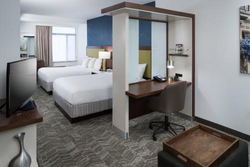 a hotel room with a bedroom with a desk and a bed at SpringHill Suites Alexandria Southwest in Alexandria