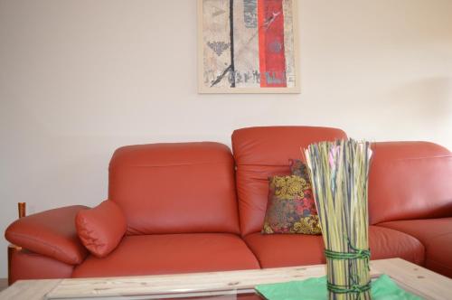 a red couch sitting in a living room with a table at Landhaus Zum Heidewanderer mit THERMEplus in Bad Bevensen