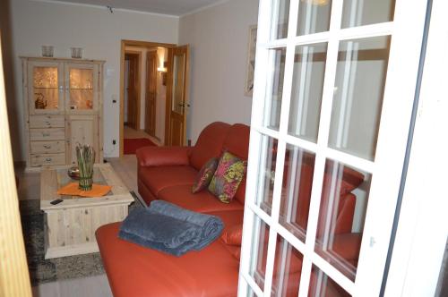 a living room with a red couch and a table at Landhaus Zum Heidewanderer mit THERMEplus in Bad Bevensen