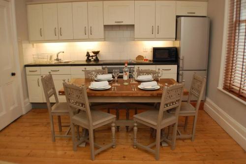 a kitchen with a table with chairs and a refrigerator at 2 Bedroom Boutique Maisonette on Kings Road, St Leonards on Sea in St. Leonards