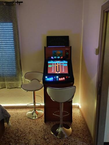 a pinball machine with two stools in a room at Arcade central retro apartment in Rethymno Town
