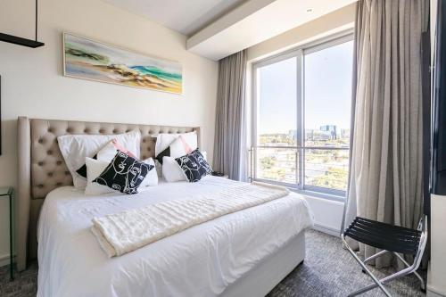 Johannesburg的住宿－Luxury 5-Star Hotel Apartment in Sandton，卧室配有白色的床和大窗户