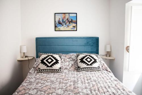 a bedroom with a bed with a blue headboard and pillows at Amber in the centar in Kaštela