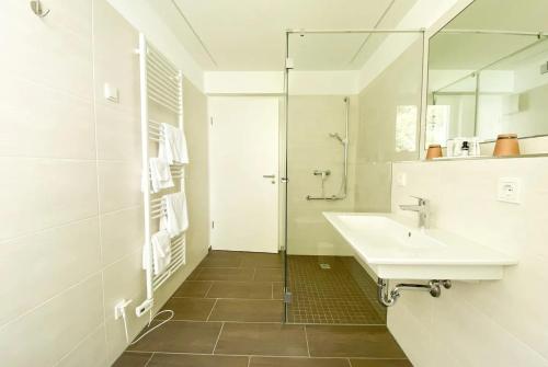 een witte badkamer met een wastafel en een douche bij Appart-Hotel Ernz Noire in Grundhof