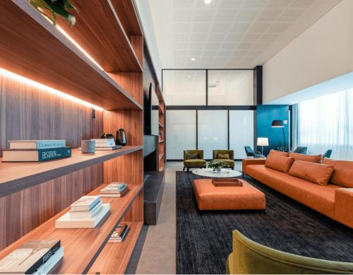 ein Wohnzimmer mit einem orangenen Sofa und Stühlen in der Unterkunft MyHome - Suíte de Luxo próximo ao Shopping Iguatemi e Consulado Americano in Porto Alegre