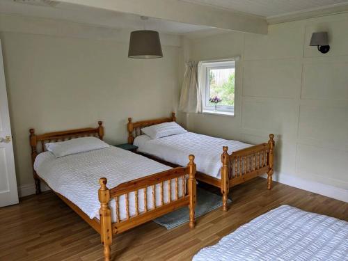 two twin beds in a room with a window at Cosy Cottage Crundale 