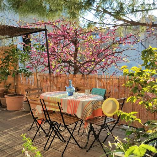 une table et des chaises sur une terrasse avec un arbre à fleurs dans l'établissement Little house with a large roof garden in the city center, à Marseille