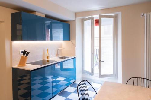 a kitchen with blue cabinets and a table at Palazzo Scappi Gardi Luxury Apartments in Bologna