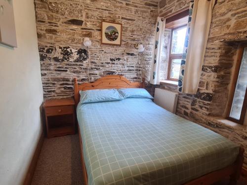 a bedroom with a bed and a brick wall at Sandpiper Cottage in Llanboidy