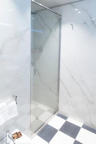 a glass shower in a bathroom with a checkered floor at Palazzo Scappi Gardi Luxury Apartments in Bologna
