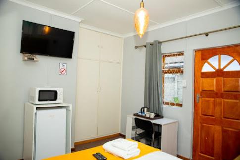 a bedroom with a bed and a desk and a television at Zakumi Guesthouse in Kokstad