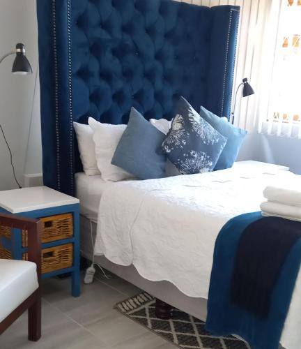 a bedroom with a blue headboard and a bed with pillows at Zakumi Guesthouse in Kokstad