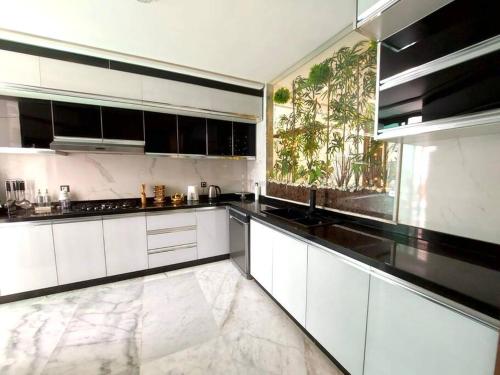 duża kuchnia z białymi szafkami i czarnymi urządzeniami w obiekcie Appartement FES Hayat Luxury w Fezie