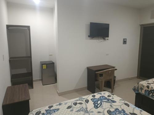 a room with a bed and a tv and a desk at Hotel Romo in Los Mochis