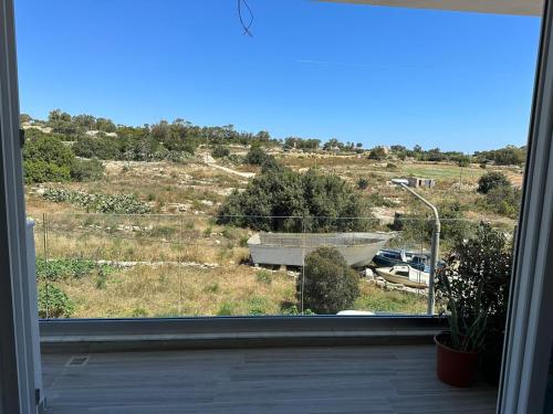 una ventana con vistas a un campo y una casa en ONE100 apartments en Marsaxlokk