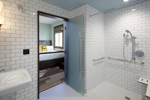 a bathroom with a shower and a sink and a bed at Moxy Santa Barbara in Santa Barbara