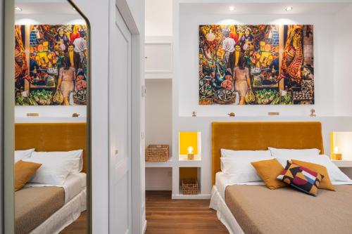 two beds in a room with two paintings on the wall at Casa Brezi in Palermo