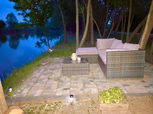 a couch sitting on a brick patio next to a body of water at Hacienda Verde in Szentes