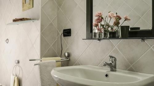 a bathroom with a sink and a mirror and flowers at Terre del Sud in Locri