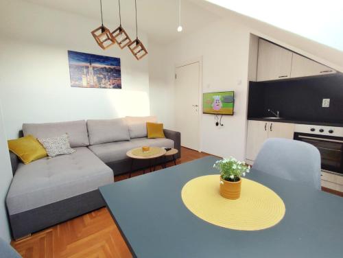 a living room with a couch and a table at Apartman NS Dan FREE PARKING in Novi Sad