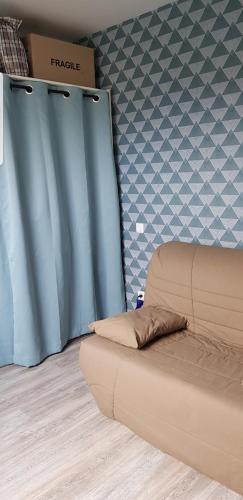 ein Sofa in einem Zimmer mit einem blauen Vorhang in der Unterkunft Chambre proche circuit 500 m du virage de Mulsanne in Mulsanne