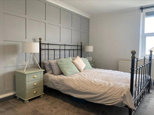 una camera da letto con letto con cuscini e comodino di Dragon Parade Apartment a Harrogate