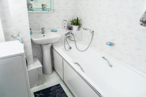 een witte badkamer met een wastafel, een bad en een toilet bij Золотой квадрат 60 кв2 in Alma-Ata