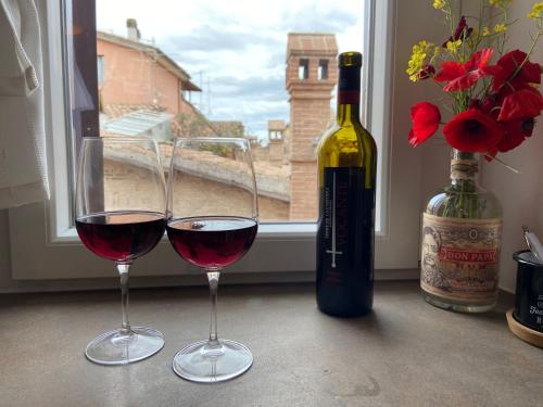 two glasses of red wine next to a bottle of wine at Casa di Lucy Umbria in Foligno