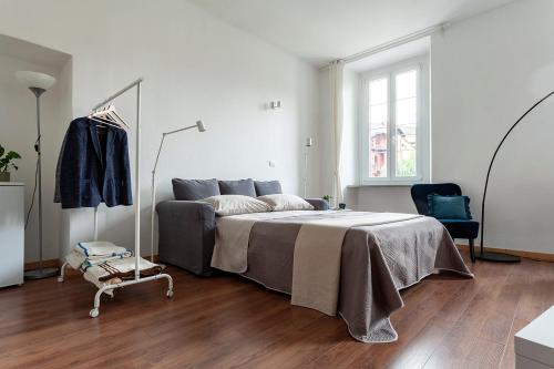 a white bedroom with a bed and a chair at A central quiet sunny studio in Verbania in Verbania