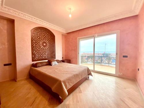 a bedroom with a large bed and a large window at Villa Belle Plage Dar Bouazza in Casablanca