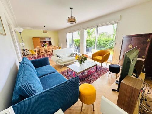 un salon avec un canapé bleu et une télévision dans l'établissement Maison d’architecte - plages, à Larmor-Plage