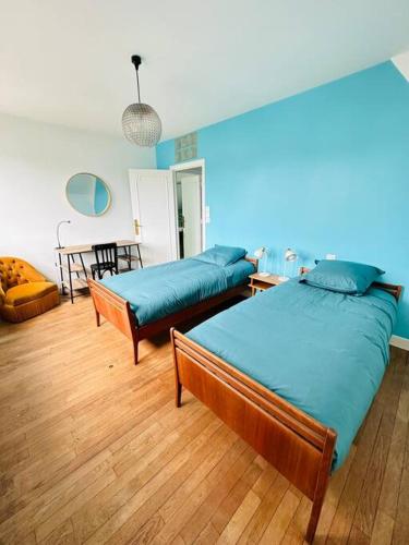 Ce lit se trouve dans un dortoir doté de murs bleus et de parquet. dans l'établissement Maison d’architecte - plages, à Larmor-Plage