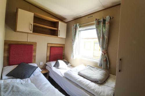 two beds in a small room with a window at Brilliant 8 Berth Caravan Near Walton-on-the-naze In Essex - 17023nm in Walton-on-the-Naze