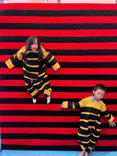 a boy and a girl are standing on a red and black wall at Flushing Garden Hotel in Queens