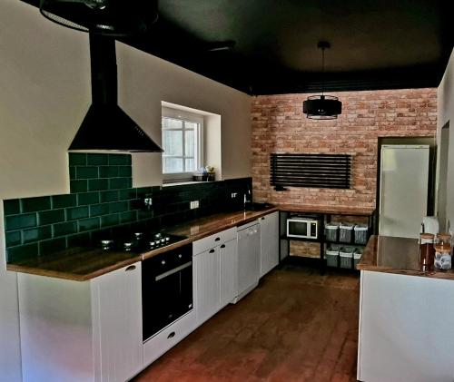 a kitchen with white cabinets and a brick wall at Mazurski Kubryk in Ruciane-Nida
