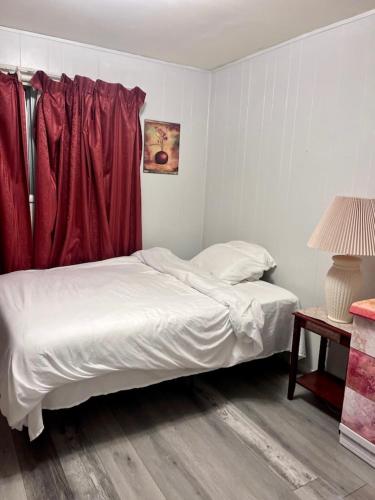 a white bed in a room with red curtains at Shaligohomes @ 4425 E 6th Ave in Anchorage