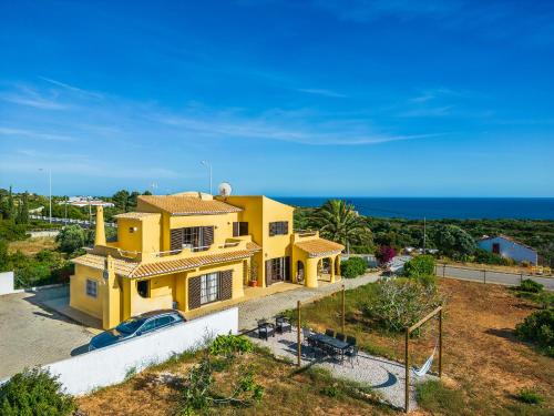 a yellow house with the ocean in the background at Casa do Mar Beach & Country Algarve in Lagoa